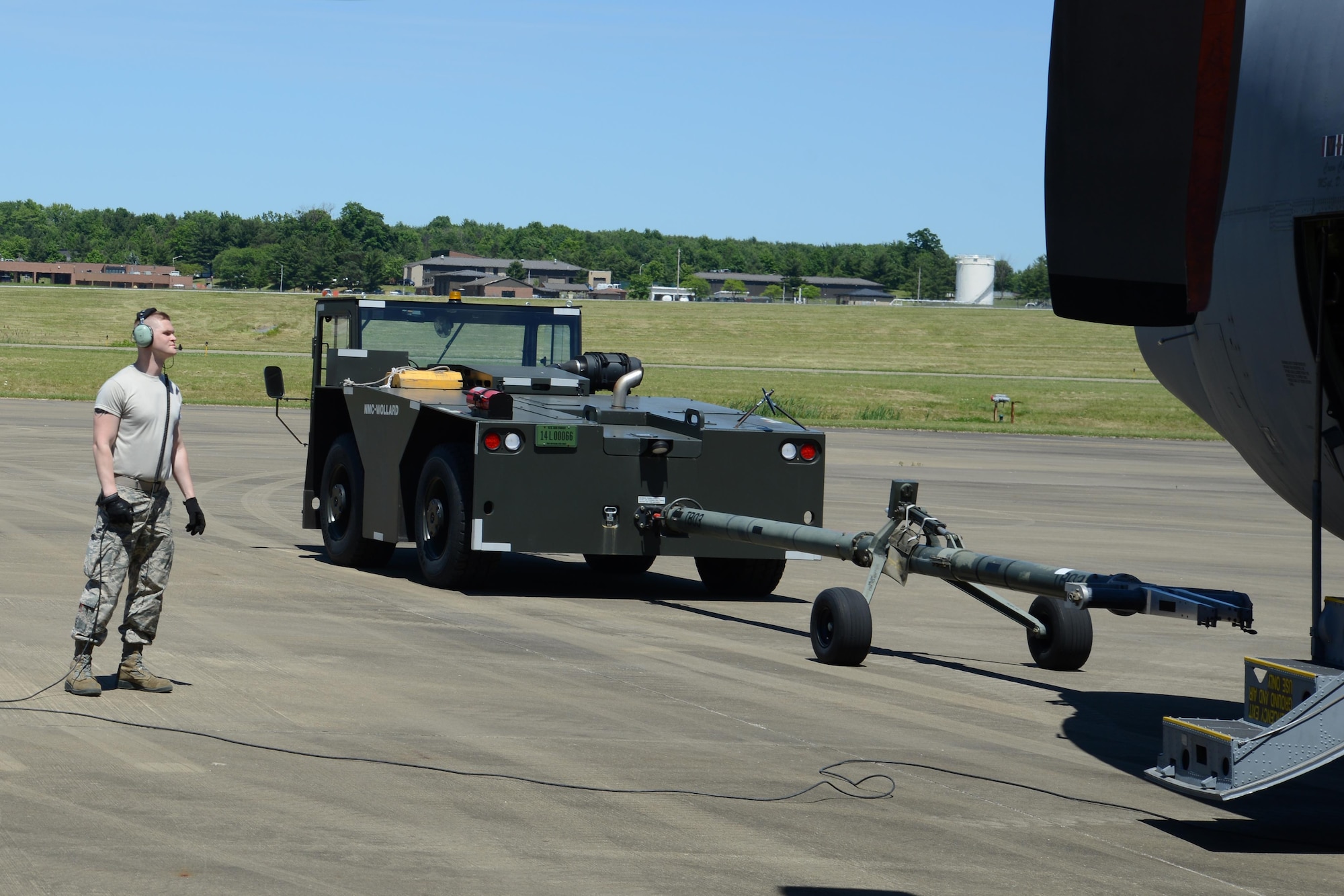 Senior Airman Taylor Webber, a C-130 crew chief with the 910th Aircraft Maintenance Squadron, communicates with the tow team of a C-130 Hercules aircraft here June 14, 2016. Maintenance uses teams of spotters and operators to ensure safe aircraft towing between hangars and parking spots. (U.S. Air Force photo/Tech. Sgt. James Brock)