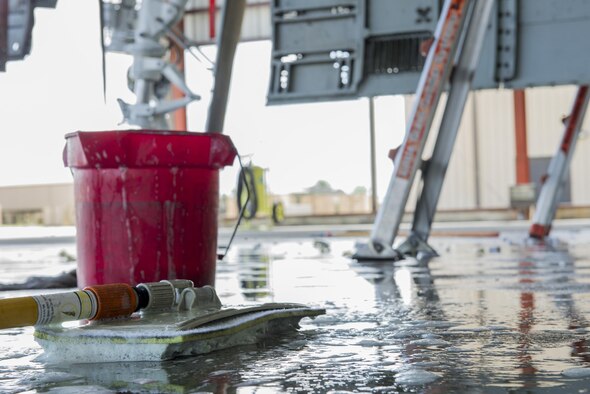 Aircraft washing materials rest on a wet floor during an A-10C Thunderbolt II wash, June 16, 2016, at Moody Air Force Base, Ga. Strong chemicals are used to clean the aircraft in order to eat away the residue weapons systems leave behind. (U.S. Air Force photo by Airman Daniel Snider/Released)