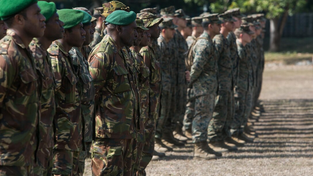 Papua New Guinea soldiers and U.S. Marines and Sailors stand in formation during the opening remarks for Exercise Koa Moana, June 18, 2016, at Taurama Barracks, Papua New Guinea. The multi-national, bilateral exercise is designed to improve interoperability and relations through mil-to-mil training and by sharing infantry, engineering, medical and law enforcement skills.