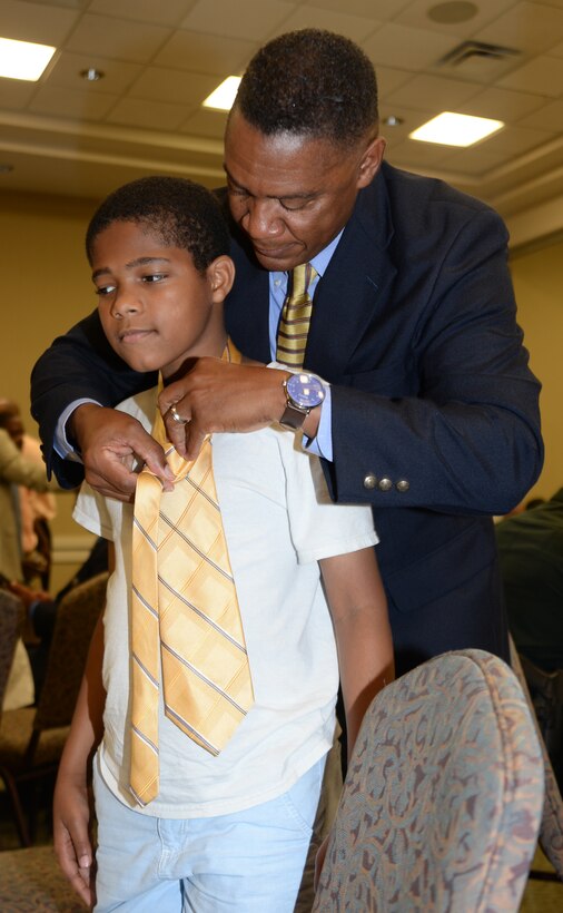 Maj. Gen. Craig Crenshaw, commanding general, Marine Corps Logistics Command, teaches a young boy how to properly tie a neck during the 2nd annual Ties that Bind event, June 16.  This event, sponsored by Phoebe Putney Memorial Hospital’s Network of Trust bonded 50 local men with 50 boys throughout the community using neck ties and sharing life lessons.