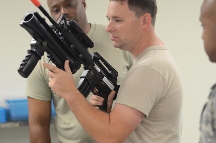 U.S. Army Reserve Soldiers from the 339th Military Police Company out of Davenport, Iowa, and the 138th MP Detachment out of Fort Bragg, N.C., inspect a weapon used in the Dismounted Soldier Training System (DSTS) during exercise Guardian Justice at Fort McCoy, Wisc., June 21, 2016. The DSTS prepares soldiers for real world challenges through practice in a virtual environment.  (U.S. Army photo by Spc. Adam Parent)