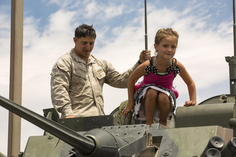 Cpl. Johnathan Tomaino, light armored vehicle crewman, 3rd Light Armored Reconnaissance Battalion, escorts Jenna Hurd, 5, as she explores a light armored vehicle during the Joshua Tree Community Days Summer Splash at the Joshua Tree Community Center in Joshua Tree, Calif., June 18, 2016. (Official Marine Corps photo by Lance Cpl. Levi Schultz/Released)