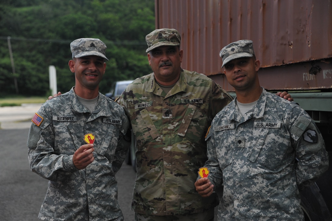 1st MSC, Commanding Sgt. Maj. Harry Muñoz., awards Sgt. Kris Gutierrez and Spc. Angel Fontanez from the 390th SPOC with the 1st MSC Command Team coin for their excellent work as the RTCH Operator and Mechanic.