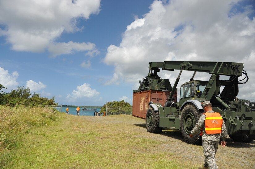 The operator of the RTCH, Sgt. Kris Gutierrez, 390th SPOC, is moving towards the LCM to place the container on it. On the corner right is PFC Luis Arzon assisting the operator.