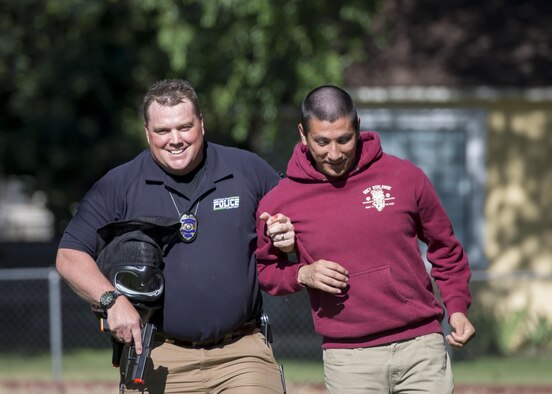 A local law enforcement member escorts a simulated victim out of a building during an active shooter exercise June 23, 2016, in downtown Mountain Home, Idaho. Local law enforcement were the first on scene and cleared the building during the exercise.(U.S. Air Force photo by Senior Airman Jeremy L. Mosier/Released)