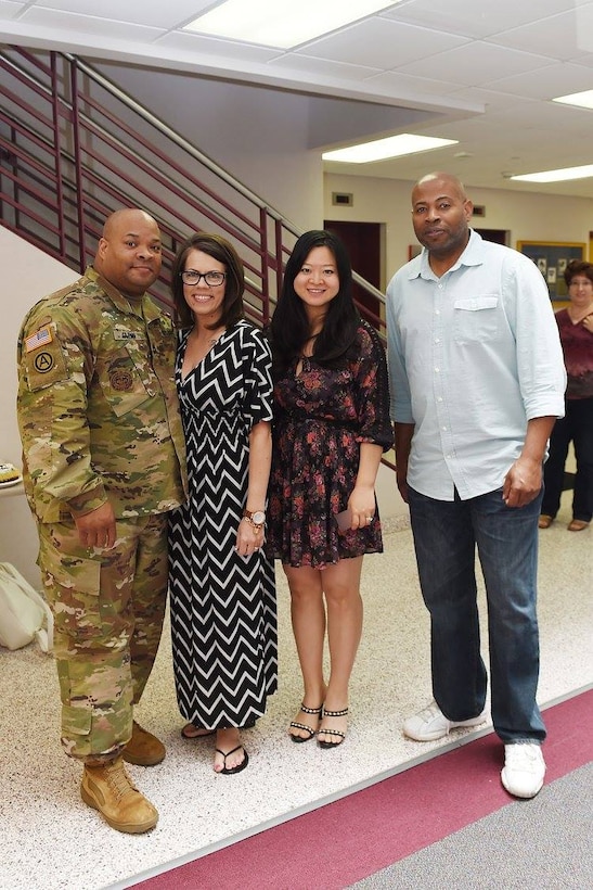 Army Reserve Sgt. 1st Class Kyle Glenn, left, G2 Physical Security Sergeant, 85th Support Command, pauses for a photo with his wife, Jessinda, second from left; Jiaru Bryar, Internal Review Officer, and Steven Bridgeforth, right, Information Technology Supervisor, following a farewell ceremony at the command headquarters. 
(Photo by Mr. Anthony L. Taylor)