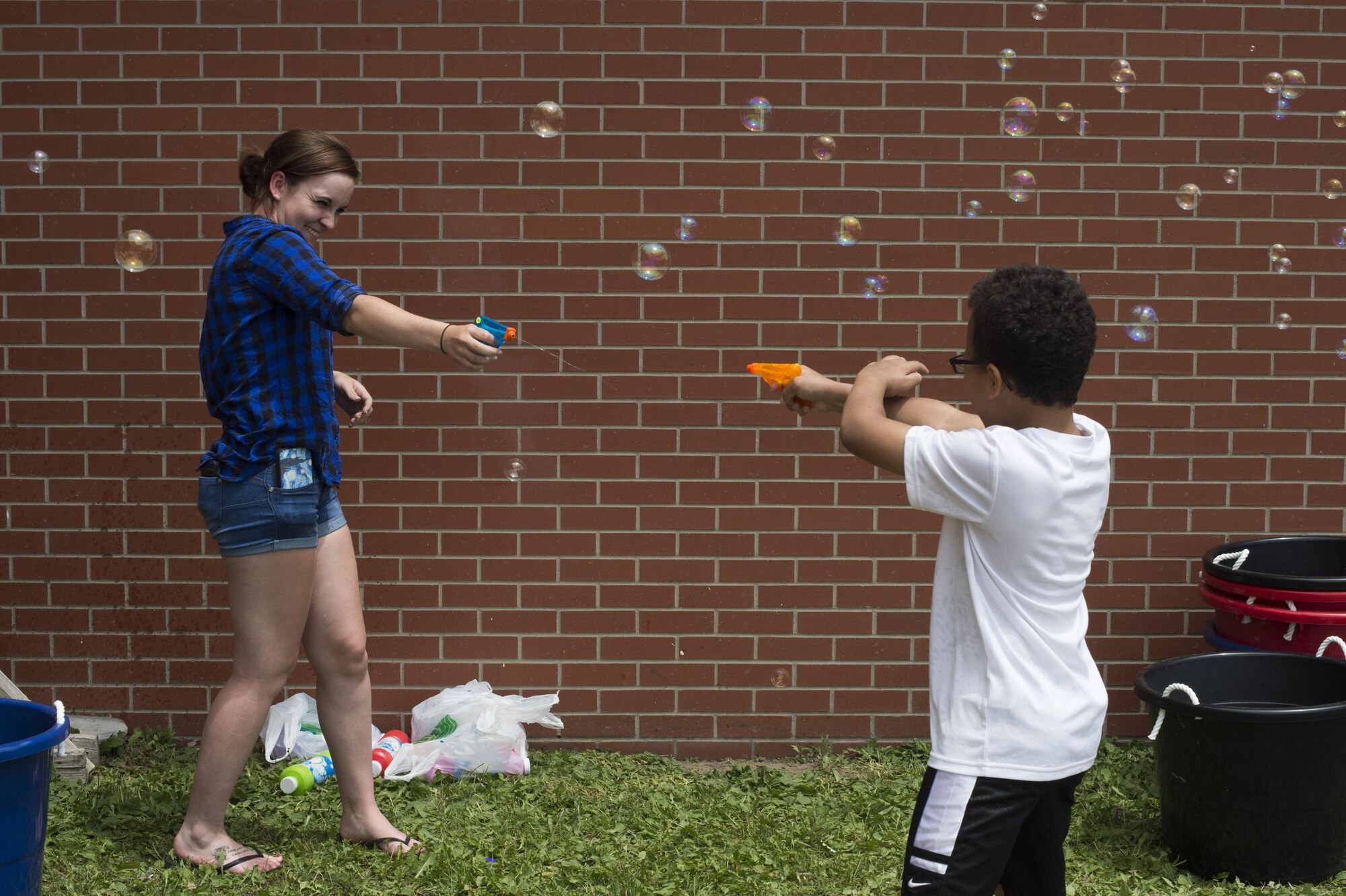 Airman Kylee Stroud, 790th Missile Security Forces Squadron security force member, engages in a water gun fight with a child during the Joint Services Multicultural Event at F.E. Warren Air Force Base, Wyo., June 22, 2016. Bouncy houses, a fire truck display and other activities were available at the event for children to enjoy. (U.S. Air Force photo by Staff Sgt. Christopher Ruano)