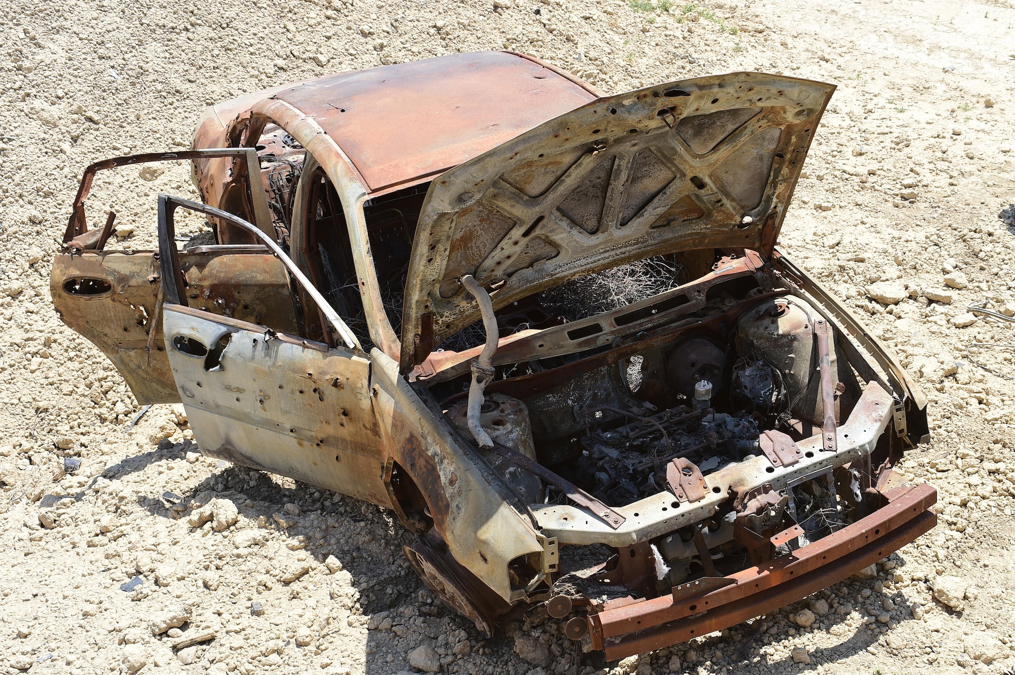 A vehicle in the blast pit is used to measure the combined explosive power of C-4, a 40-pound shape charge and detonation cord June 23, 2016, at the Airburst Range on Fort Carson, Colo. 140th Explosive Ordnance Disposal operators placed C-4 on the engine block, a 40-pound shape charge in a crater underneath the vehicle and taped detonation cord to the top of the vehicle to see the effects of each. (U.S. Air Force photo by Airman 1st Class Luke W. Nowakowski/Released)