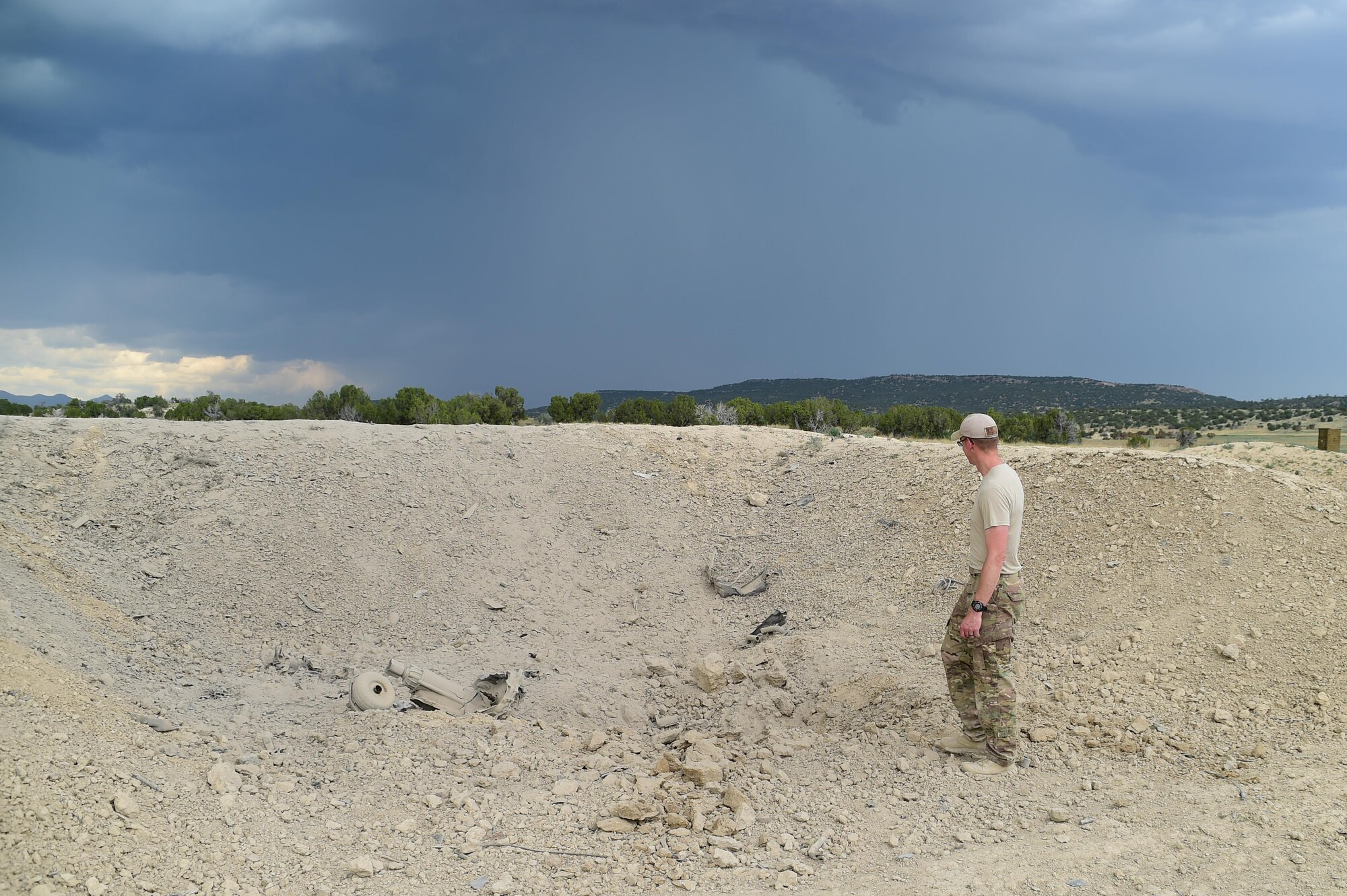 Airman 1st Class Thomas Benedict, 140th Explosive Ordnance Disposal operator, stands in front the empty blast pit which is now void of the vehicle June 23, 2016, at the Airburst Range on Fort Carson, Colo. The blast had picked up the vehicle and thrown it 50 feet on the other side of the blast pit. (U.S. Air Force photo by Airman 1st Class Luke W. Nowakowski/Released)