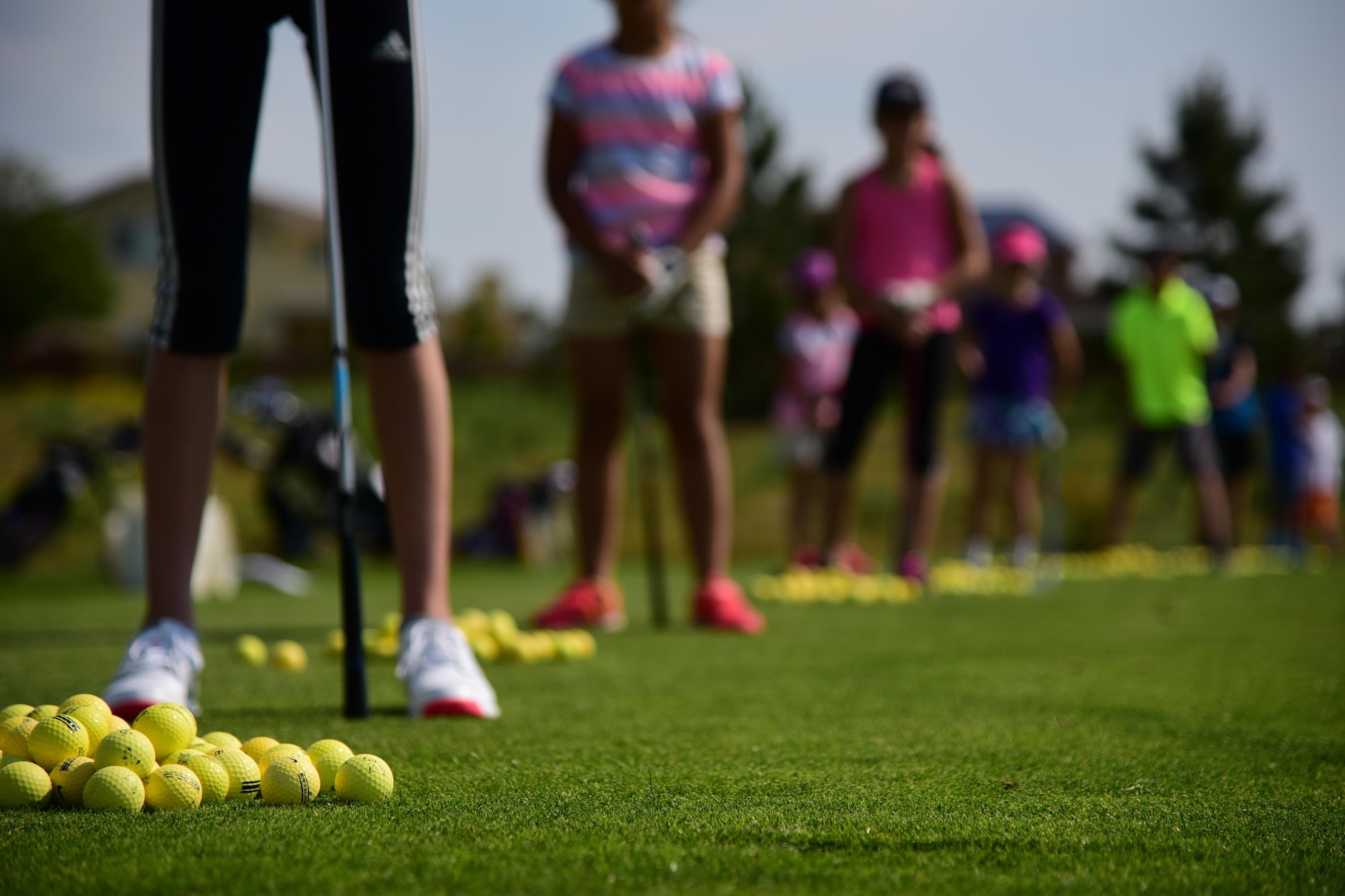 PETERSON AIR FORCE BASE Colo. - Young golfers line up to practice their swings at the Silver Spruce Golf Course driving range on Peterson Air Force Base, Colo., June 22, 2016. The children benefited from individual time with instructors as they work to improve their game during a week-long Junior Golf Clinic. (U.S. Air Force photo by Staff Sgt. Amber Grimm)