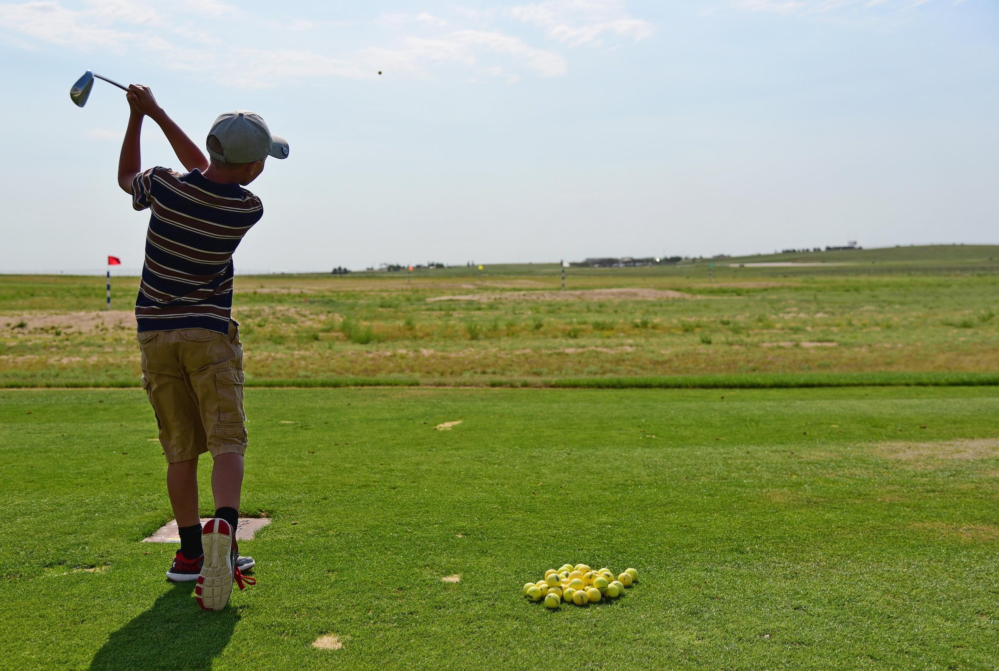 PETERSON AIR FORCE BASE Colo. - A young golfer swings away on the Silver Spruce Golf Club driving range at Peterson Air Force Base, Colo., June 22, 2016. Children between the ages of 6 and 17 came together to participate in a five-day golf camp to improve their game. (U.S. Air Force photo by Staff Sgt. Amber Grimm)