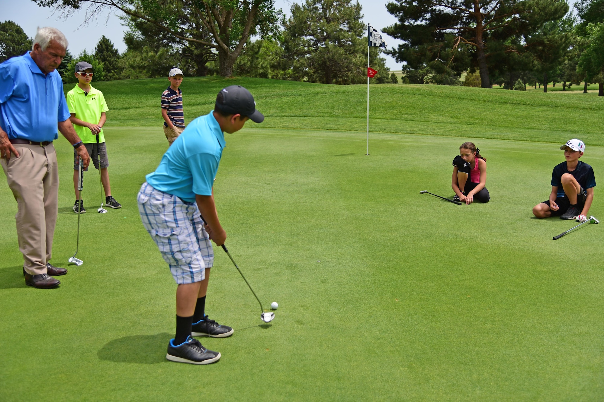 PETERSON AIR FORCE BASE Colo. - Young golfers line up to practice their swings at the Silver Spruce Golf Course driving range on Peterson Air Force Base, Colo., June 22, 2016. The children benefited from individual time with instructors as they work to improve their game during a week-long Junior Golf Clinic. (U.S. Air Force photo by Staff Sgt. Amber Grimm)