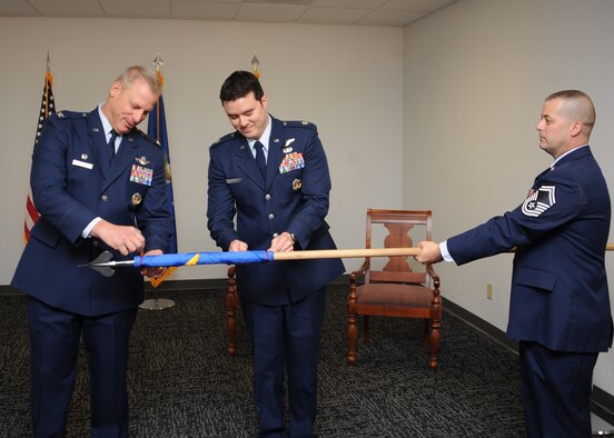 U.S. Air Force Col. Gregory Marzolf, 414th Combat Training Squadron, commander,  Lt. Col. Christopher Cunningham, Detachment 1, 414th CTS, commander and Senior Master Sgt. Stephen Hoss, 414th CTS, Red Flag superintendent, unroll the guidon of Detachment 1 at Davis-Monthan Air Force Base, Ariz., June 24, 2016. The new detachment will be planning, coordinating and executing Angel Thunder 2016. (U.S. Air Force photo by Airman 1st Class Ashley N. Steffen/ Released)  