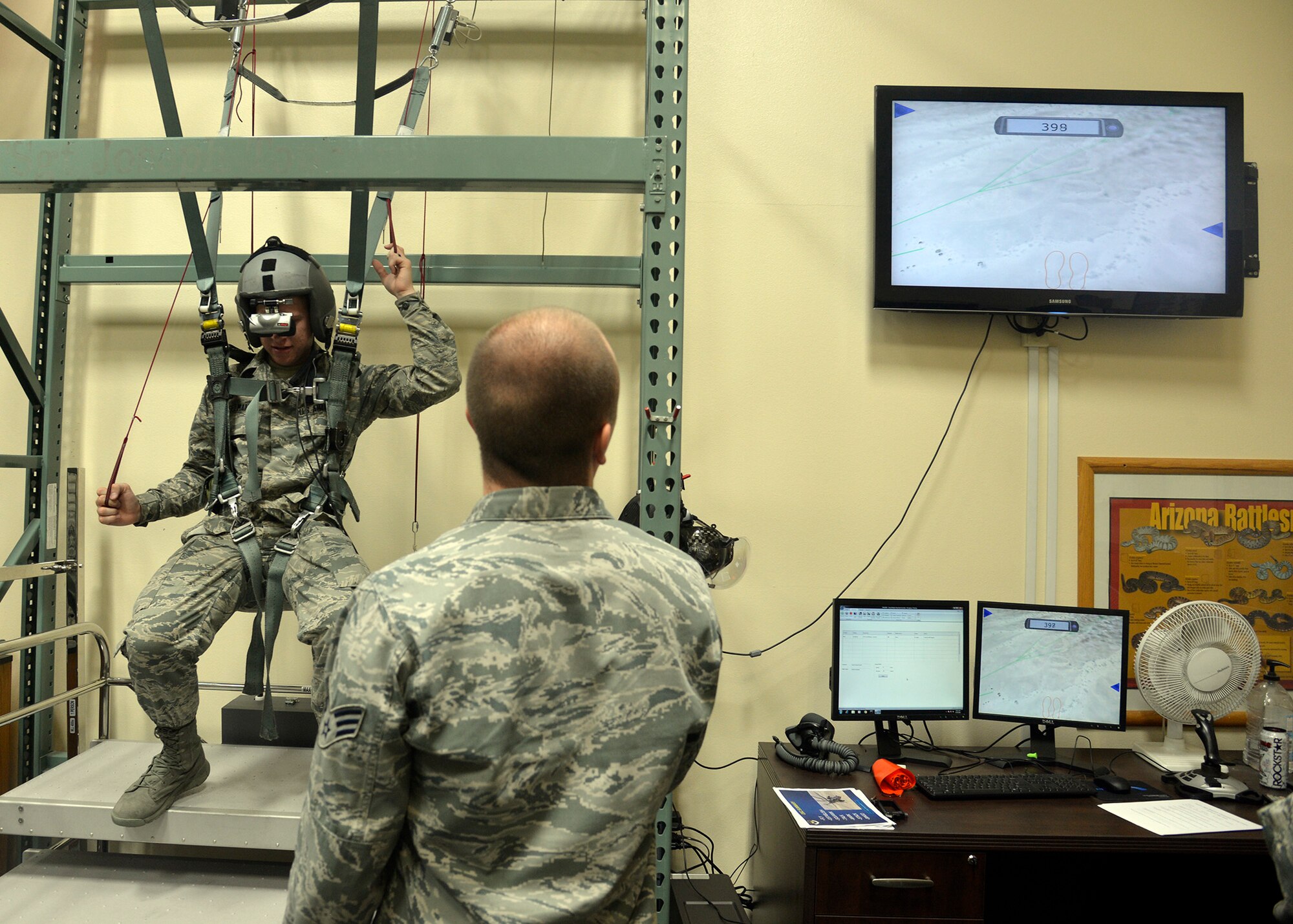 Senior Airman Bryce Gardner, 56th Operation Support Squadron aircrew flight equipment technician, watches the screen as Airman Basic Clayton Selman, 56th Fighter Wing judge advocate legal office apprentice, simultaneously steers to safety June 24, 2016 at Luke Air Force Base, Ariz. Senior Airman Zachary Newman, 56th Operation Support Squadron aircrew flight equipment, shows the Immersion Program participants the F-35 Lightning II helmet June 24, 2016 at Luke Air Force Base, Ariz. The Immersion Program gives Airmen the opportunity to experience the Air Force from a different perspective. (U.S. Air Force photo by Senior Airman Devante Williams)
