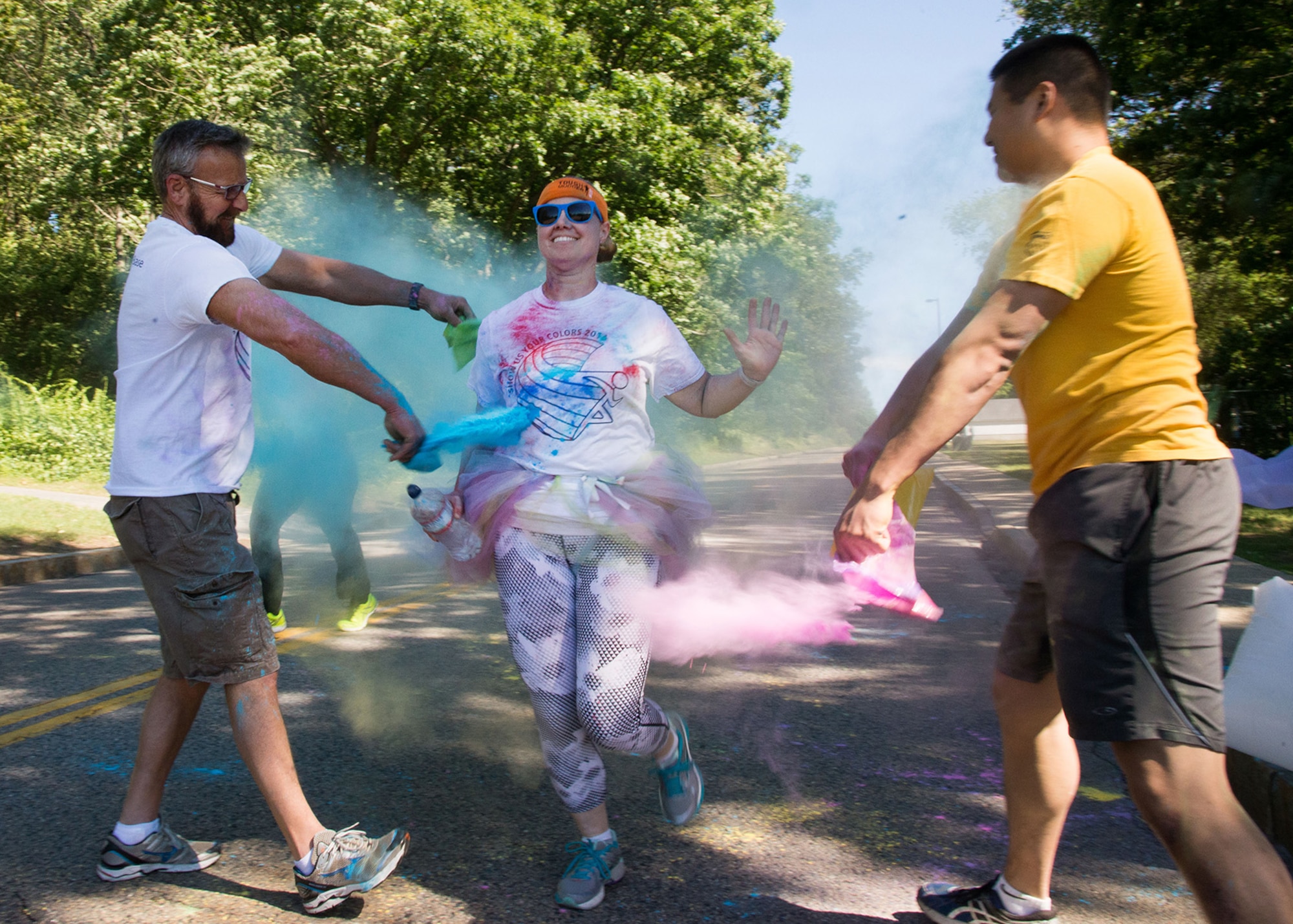 Steve Ober, left, and Capt. Ken Suen, Lesbian, Gay, Bisexual and Transgender Pride Month committee members throw colored powder over Master Sgt. Jessica Labrie, 66th Air Base Group first sergeant, during a Pride Month color run at Hanscom Air Force Base, Mass., June 22. Throughout the month, the Department of Defense has recognized all LGBT members of the workforce for their dedicated service to both the DOD and nation.  (U.S. Air Force photo by Mark Herlihy)