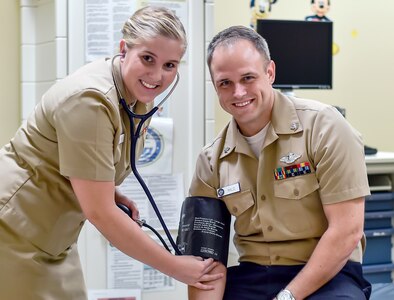 Lt. Samantha Favreau, Naval Health Clinic Charleston medical home port blue team lead, smiles while checking Petty Officer 3rd Class Dallas Wilder’s, a NHCC medical home port blue team floor supervisor, blood pressure at the Joint Base Charleston-Weapons Station NHCC, June 17, 2016. Favreau is planning a trip to Virginia for the 4th of July to spend time with her family. Favreau says the holiday is a reminder of the United States’ relentless pursuit of liberty and justice for all. (U.S. Air Force Photo/Airman Megan Munoz)