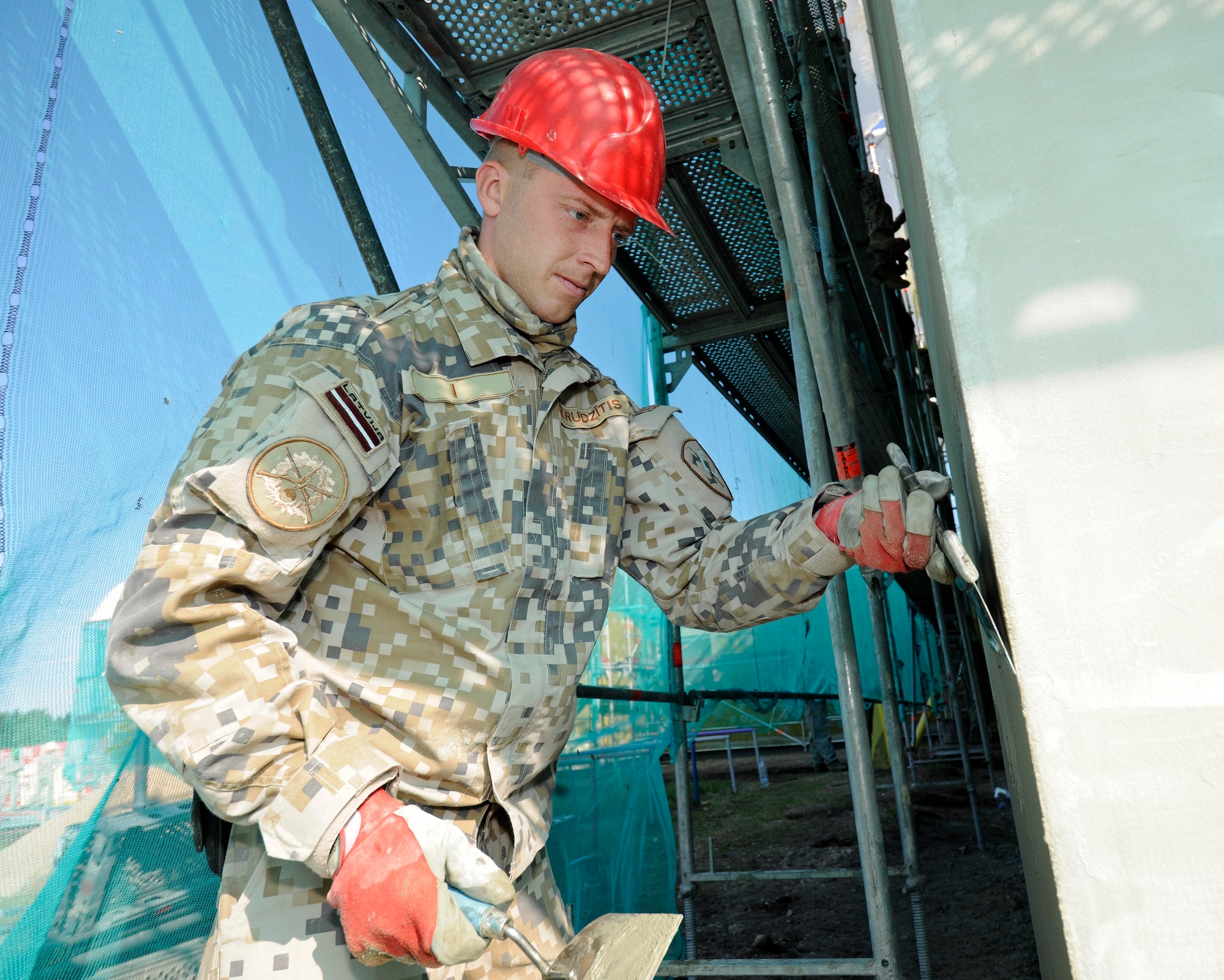 Private First Class Rihards Rudzitis, Latvian National Armed Forces, works on the side of a kindergarten building in Silmala, Latvia on June 19, 2016. The school is undergoing construction as part of the U.S. European Command’s Humanitarian Civic-Assistance project. United States and Latvian military engineers are working together to complete the project. (U.S. Air National Guard photo by Senior Airman Ryan Zeski)