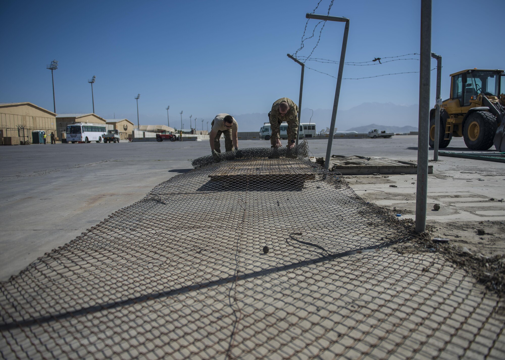 1st Lt. Paul Dennison (left), 455th Expeditionary Civil Engineer Squadron flight chief, and 1st Lt. Pablo Fernandez (right), 455th ECES operations flight chief, rolls a fence during a building demolition, June 22, 2016, Bagram Airfield, Afghanistan. The old petroleum, oil, and lubricant building is being demolished to make way for a new facility. (U.S. Air Force photo by Senior Airman Justyn M. Freeman)