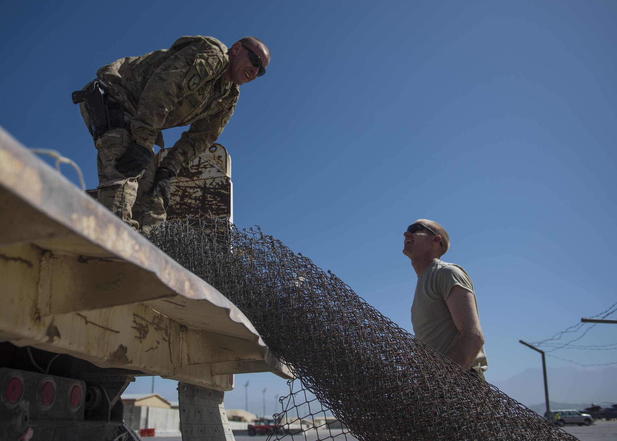 1st Lt. Pablo Fernandez (left), 455th Expeditionary Civil Engineer Squadron operations flight chief, and 1st Lt. Mark Bohme (right), 455th ECES project engineer, lifts a rolled up fence during a building demolition, June 22, 2016, Bagram Airfield, Afghanistan. Developmental engineers plan, organize, and implement systems engineering processes as well as identify and incorporate new technology. (U.S. Air Force photo by Senior Airman Justyn M. Freeman)
