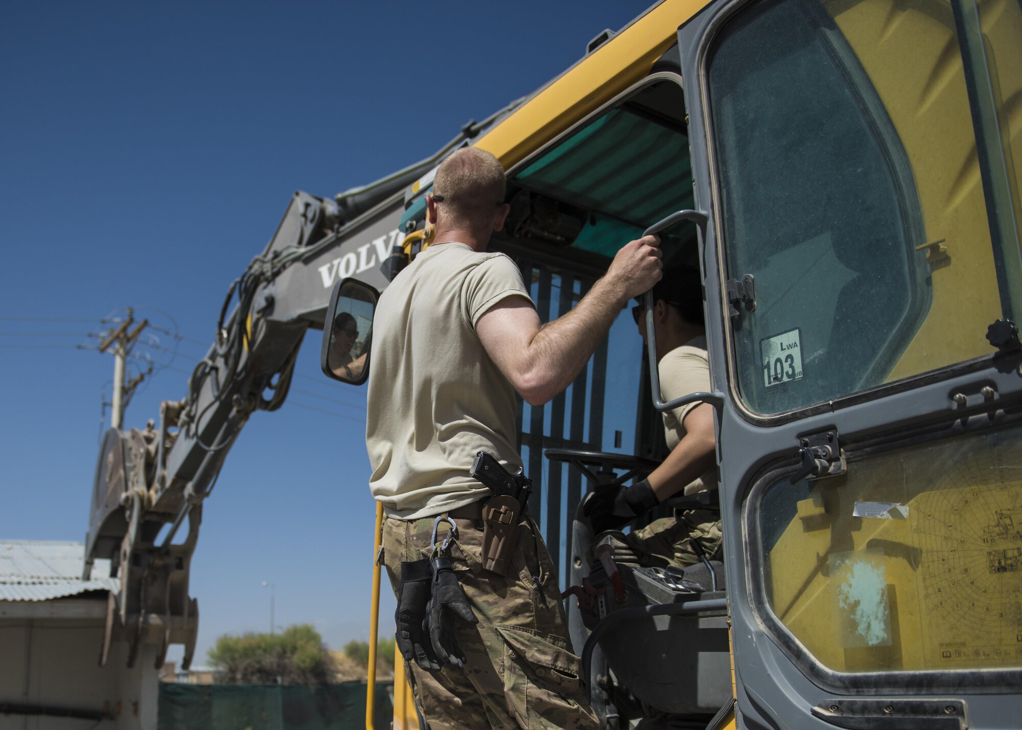 1st Lt. Mark Bohme (left), 455th Expeditionary Civil Engineer Squadron project engineer, helps Capt. Ainslie Vizcarra (right), 455th Expeditionary Mission Support Group command executive, operate an excavator during a building demolition, June 22, 2016, Bagram Airfield, Afghanistan. The old petroleum, oil, and lubricant building is being demolished to make way for a new facility. (U.S. Air Force photo by Senior Airman Justyn M. Freeman)