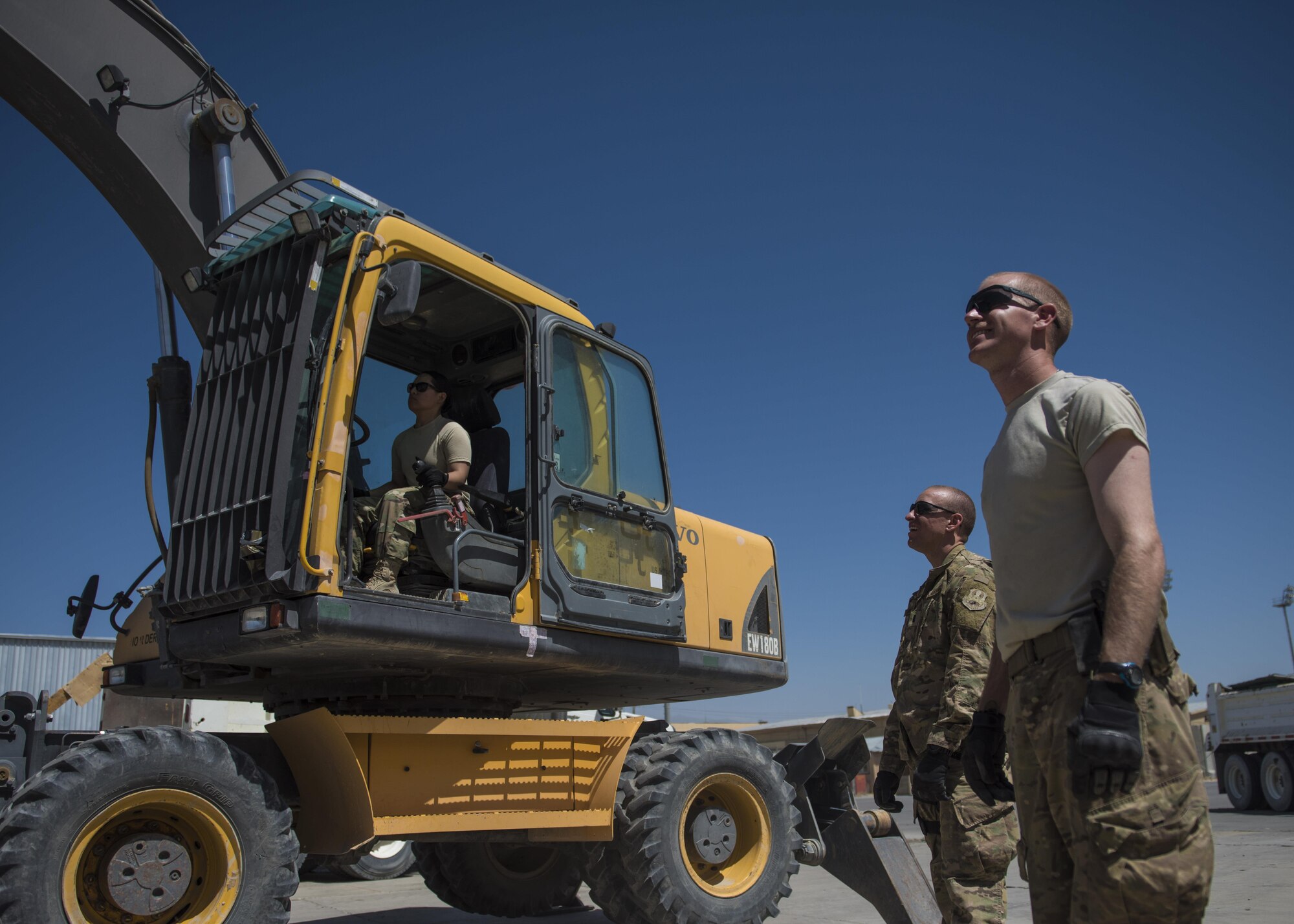 Capt. Ainslie Vizcarra (left), 455th Expeditionary Mission Support Group command executive, operates an excavator with 1st Lt. Pablo Fernandez (middle), 455th Expeditionary Civil Engineer Squadron operations flight chief, and 1st Lt. Mark Bohme, 455th ECES project engineer, watches a building demolition, June 22, 2016, Bagram Airfield, Afghanistan. Members of the 455th ECES reached out to other squadrons to help them demolish the old petroleum, oil, and lubricant building to help consolidate facilities across the base. (U.S. Air Force photo by Senior Airman Justyn M. Freeman)