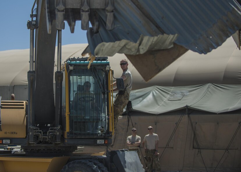 Capt. Ainslie Vizcarra (left), 455th Expeditionary Mission Support Group command executive, operates an excavator with the help of 1st Lt. Mark Bohme (right), 455th Expeditionary Civil Engineer Squadron project engineer, to demolish an old building, June 22, 2016, Bagram Airfield, Afghanistan. Members of the 455th ECES reached out to other squadrons to help demolish the old petroleum, oil, and lubricant building to consolidate buildings across the base. (U.S. Air Force photo by Senior Airman Justyn M. Freeman)