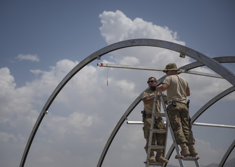 Staff Sgt. Mark Munoz (left) and Senior Airman Eric Woolston (right), 455th Expeditionary Civil Engineer Squadron, build the skeleton of a tent, June 25, 2016, Bagram Airfield, Afghanistan. The power production shop maintains the base electrical supply while heating, ventilation, and air conditioning shops maintain the mechanical systems that manage the climate within buildings. (U.S. Air Force photo by Senior Airman Justyn M. Freeman)