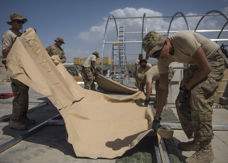Staff Sgt. James Solis (right), 455th Expeditionary Civil Engineer Squadron, slides the fabric of a tent into place, June 25, 2016, Bagram Airfield, Afghanistan. All flights within the 455th ECES, including structures, dirt boys, and electrical, came together to build a new tent to relocate the power production and heating, ventilation, and air conditioning shops. (U.S. Air Force photo by Senior Airman Justyn M. Freeman)