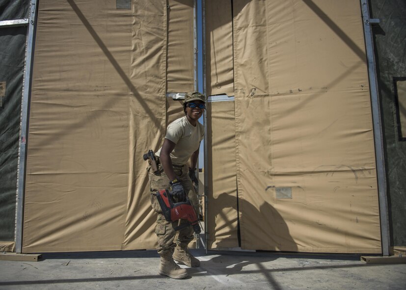 Airman 1st Class Taylor Davis, 455th Expeditionary Civil Engineer Squadron structural journeyman, closes a tent door, June 25, 2016, Bagram Airfield, Afghanistan. Davis is drilling holes in the ground to support the tent doors. (U.S. Air Force photo by Senior Airman Justyn M. Freeman)