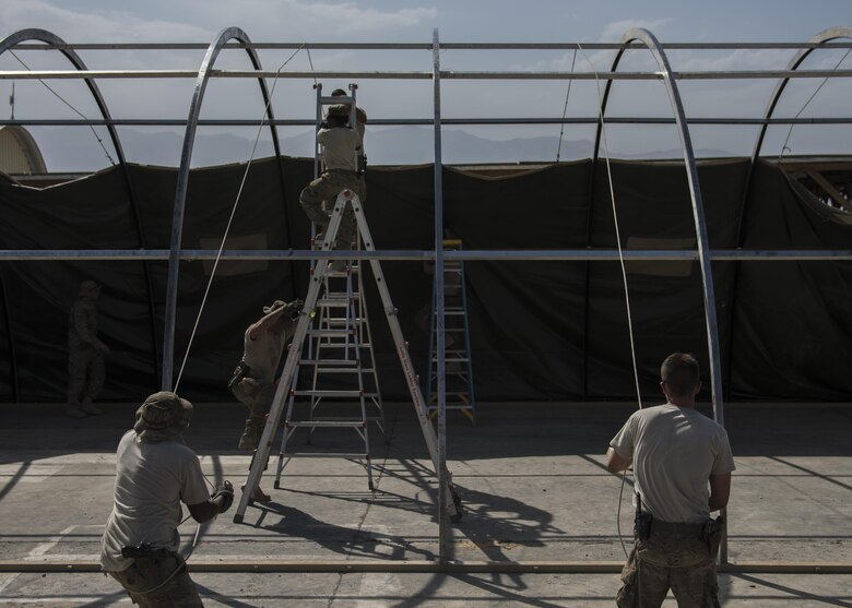 Staff Sgt. Donald Scott (left) and Senior Airman Jonathan Brooks (right), 455th Expeditionary Civil Engineer Squadron, pull up a tent cover, June 25, 2016, Bagram Airfield, Afghanistan. All flights within the 455th ECES, including structures, dirt boys, and electrical, came together to build a new tent to relocate the power production and heating, ventilation, and air conditioning shops. (U.S. Air Force photo by Senior Airman Justyn M. Freeman)