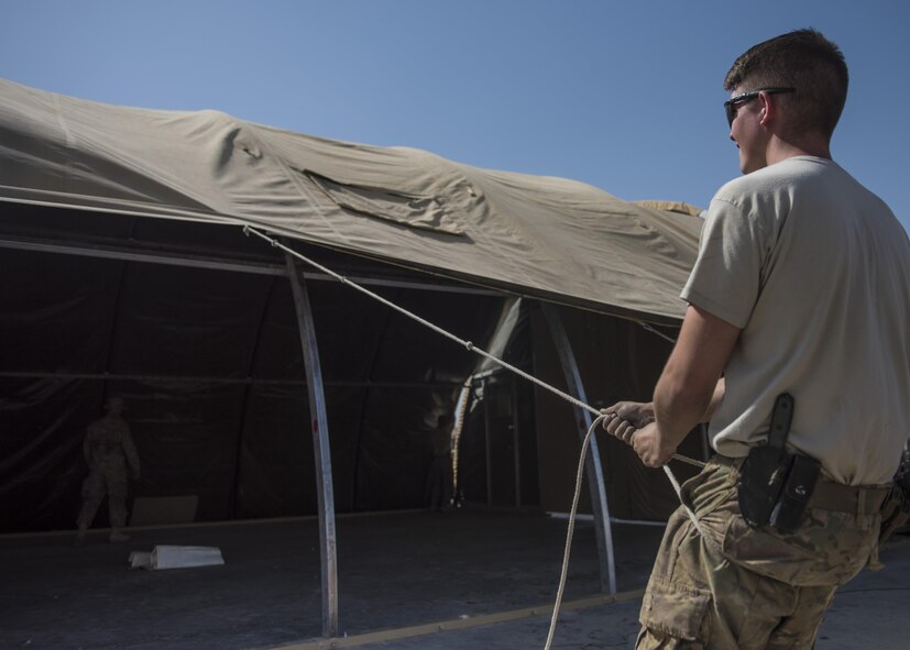 Senior Airman Jonathan Brooks, 455th Expeditionary Civil Engineer Squadron structural journeyman, pulls a tent cover down, June 25, 2016, Bagram Airfield, Afghanistan. Members of the 455th ECES structures flight construct and repair buildings and other military structures from the foundation up. (U.S. Air Force photo by Senior Airman Justyn M. Freeman)
