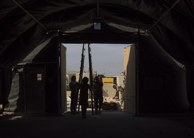 Airman from the 455th Expeditionary Civil Engineer Squadron place a ladder under the tent doorway, June 25, 2016, Bagram Airfield, Afghanistan. All flights within the 455th ECES, including structures, dirt boys, and electrical, came together to build a new tent to relocate the power production and heating, ventilation, and air conditioning shops. (U.S. Air Force photo by Senior Airman Justyn M. Freeman)