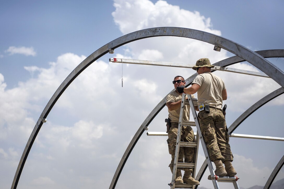 Air Force Staff Sgt. Mark Munoz, left, and Senior Airman Eric Woolston build the skeleton of a tent at Bagram Airfield, Afghanistan, June 25, 2016. Munoz and Woolston are structural journeymen assigned to the 455th Expeditionary Civil Engineer Squadron. Air Force photo by Senior Airman Justyn M. Freeman