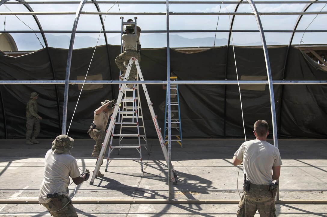 Air Force Staff Sgt. Donald Scott, left, and Senior Airman Jonathan Brooks pull up a tent cover on a frame at Bagram Airfield, Afghanistan, June 25, 2016. Scott and Brooks are structural journeymen assigned to the 455th Expeditionary Civil Engineer Squadron. Air Force photo by Senior Airman Justyn M. Freeman