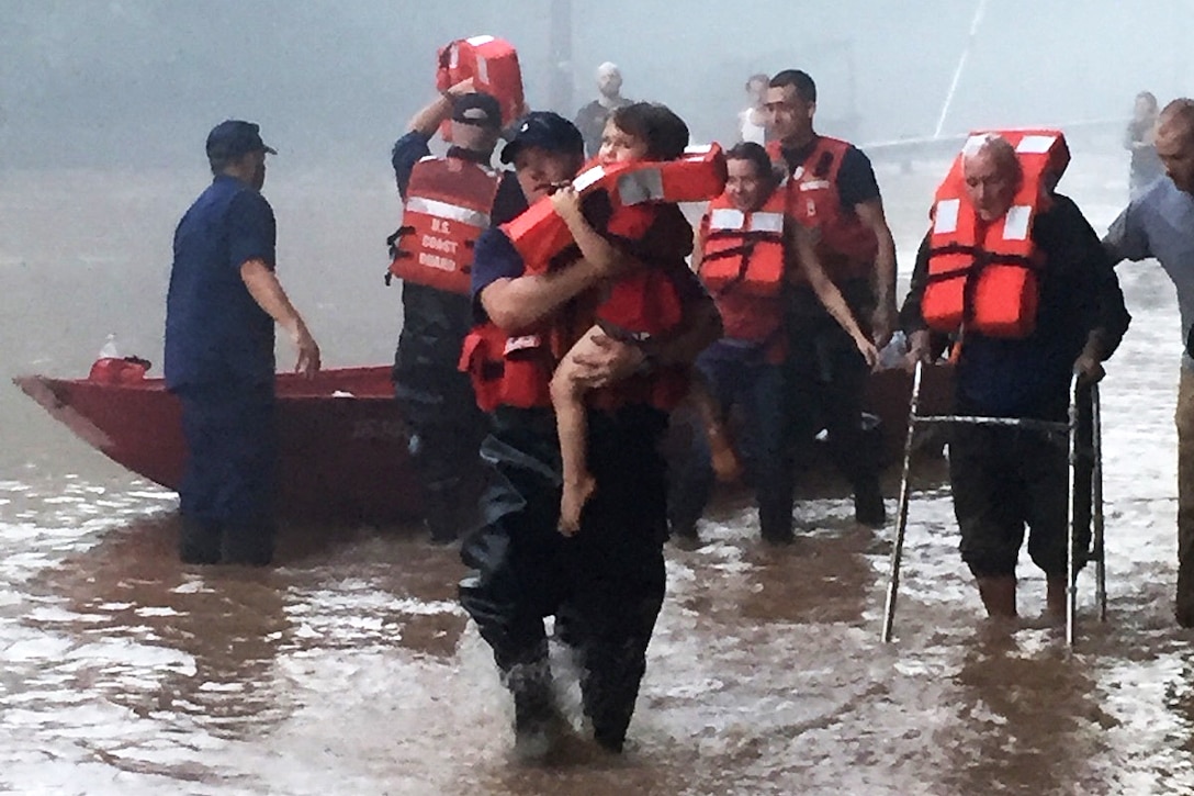 Coast Guardsmen help stranded residents to safety and a waiting multi-terrain vehicle during severe flooding in near Clendenin, W.V., June 24, 2016. Coast Guard photo