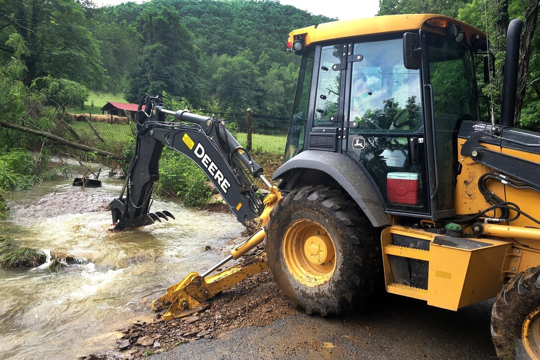 A local responder operates a backhoe to clear debris from a small stream and roadway during severe flooding in Allegheny County, Va., June 24, 2016. Army National Guard photo by Alfred Puryear
