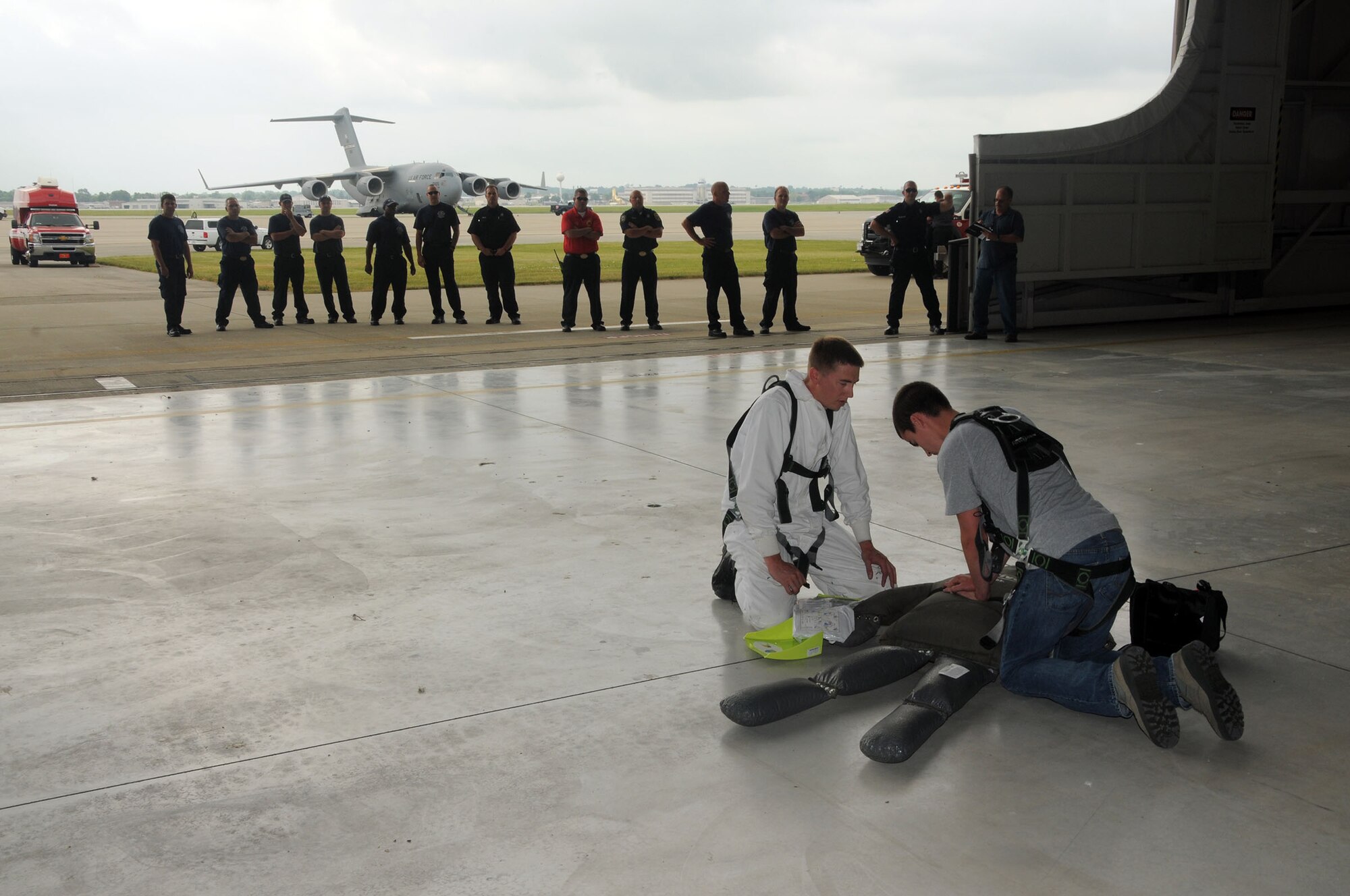 Senior Airman Barrett Lowry and Tech. Sgt. Jared Rucker, both fuel systems mechanics with the 445th Aircraft Maintenance Squadron simulate administering CPR to a training aid while members of the 88th Air Base Wing Fire Department observe during the annual Confined Space Emergency Extraction Exercise at Wright-Patterson Air Force Base, Ohio June 21, 2016. The exercise scenario was conducted to practice confined space self-rescue procedures in the extraction of an incapacitated airman from a long range fuel tank behind the #2 engine of a C-17 Globemaster III aircraft. (U.S. Air Force Photo/Tech. Sgt. Anthony G. Springer)