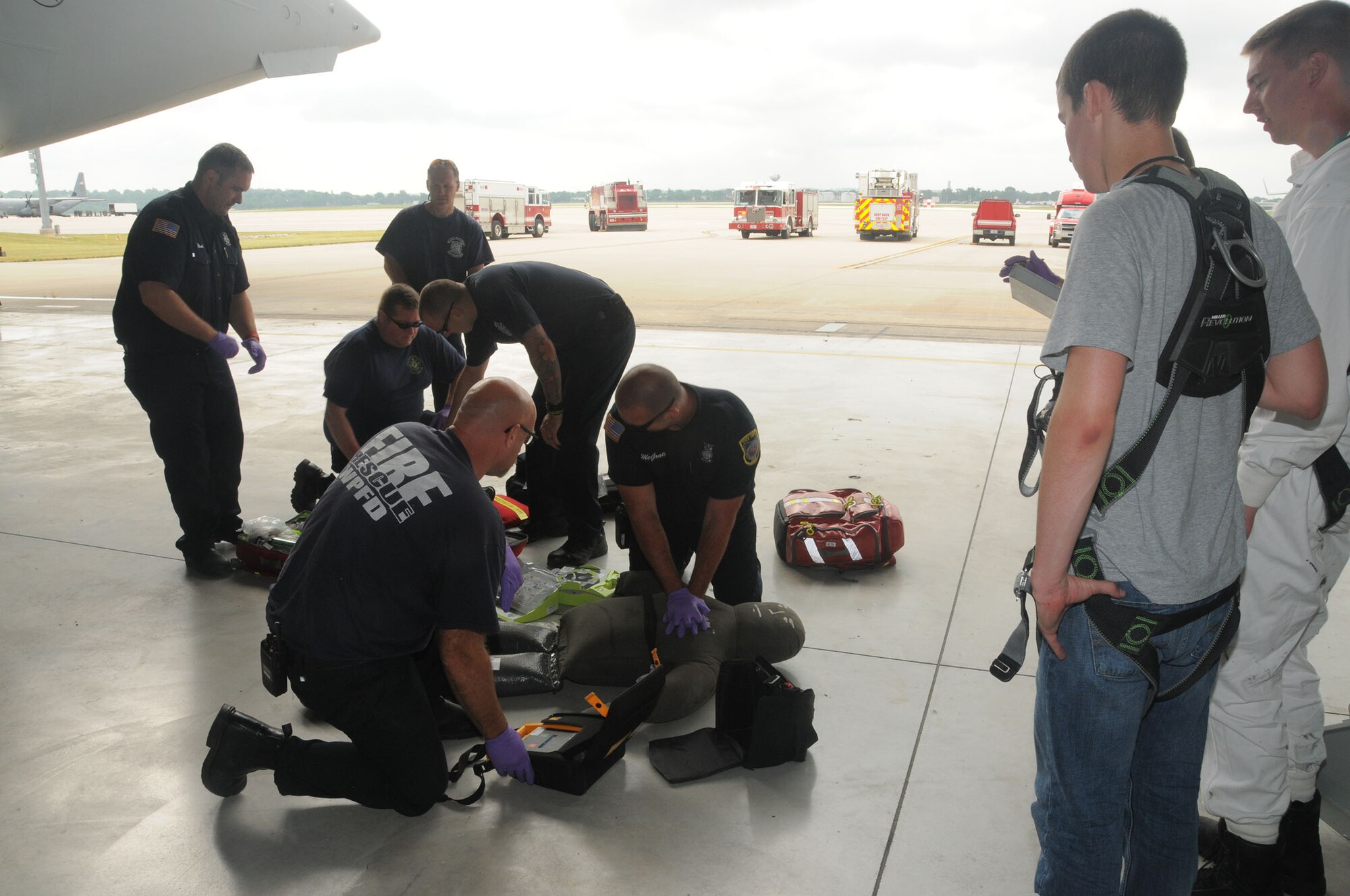 Members of the 88th Air Base Wing fire department simulate the administration of life saving techniques on a training aid while Senior Airman Barrett Lowry and Tech. Sgt. Jared Rucker, both fuel systems mechanics with the 445th Aircraft Maintenance Squadron, observe during the annual Confined Space Emergency Extraction Exercise at Wright-Patterson Air Force Base, Ohio June 21, 2016.  The exercise scenario was conducted to practice confined space self-rescue procedures in the extraction of an incapacitated airman from a long range fuel tank behind the #2 engine of a C-17 Globemaster III aircraft.    (U.S. Air Force Photo/Tech. Sgt. Anthony G. Springer)
