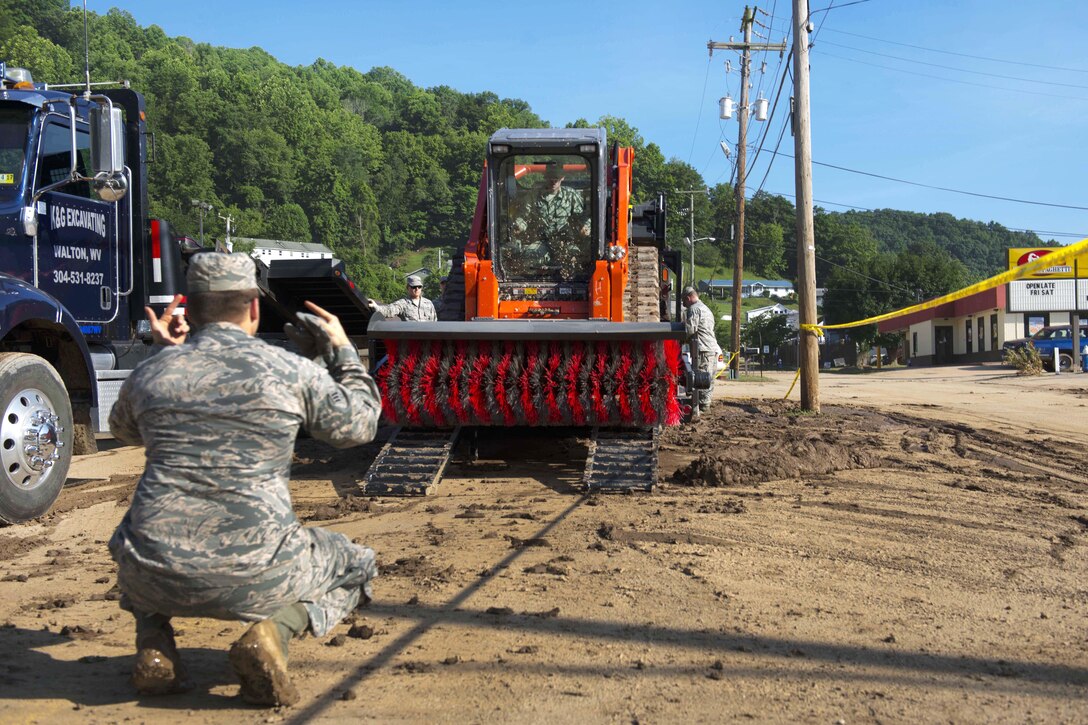 An airman directs a team member operating a street sweeper to unload from a truck in Clendenin, W.Va., June 26, 2016, while assisting with the response to severe flooding in the area. The airmen are assigned to the West Virginia Air National Guard. Air National Guard photo by Tech. Sgt. De-Juan Haley