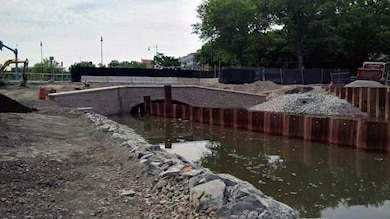 Granite veneer installed and continued backfilling behind the wing wall and shaping of the Flood Risk Management (FRM) channel on the northside.