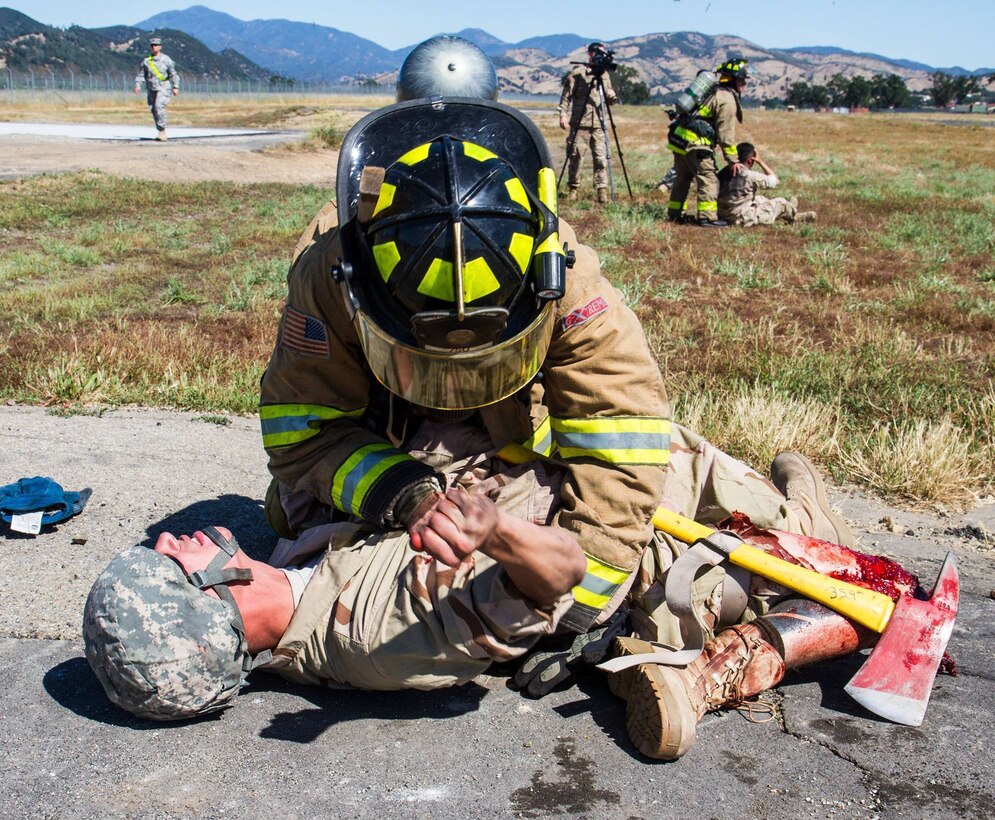 A U.S. Army firefighting Soldier participating in the WAREX training exercises hosted by 91st Training Division aids the victim of a downed helicopter scenario (simulated) on Fort Hunter Liggett, Calif. on May 9, 2016. Fire response Soldiers put out a fire in the training helicopter as other firefighters treat the casualties as part of a joint response operation.(U.S. Army photos by 1LT Kevin Braafladt 91st Training Division Public Affairs/Released)  #91TD2016WAREX