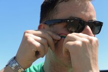 Senior Airman John King, a contract specialist assigned to the 5th Contracting Squadron, places a rainbow sticker on his cheek at the Orlando Memorial 5K at Minot Air Force Base, N.D, June 17, 2016. The race was organized by the Minot AFB Diversity Committee to pay respects to the 49 lives lost in the Orlando shooting June 12. (U.S. Air Force photo/Airman 1st Class Jessica Weissman)