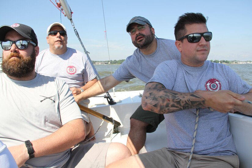 (From left) Army veteran James Hansen watches the wind’s direction as Navy veteran and Valhalla sailing instructor Frank Briguglio surveys the skills of his new recruits during the Valhalla Sailing Project’s inaugural clinic to teach former military members the fundamentals of sailing and racing on the Chesapeake Bay in Annapolis, Md., June 25, 2016. Marine Corps veteran Hector Cardona is at the tiller, and Marine Corps veteran Mike Wilson is adjusting the jib. Eight veterans, transitioning service members and wounded warriors participated in the clinic. DoD photo by Terri Moon Cronk