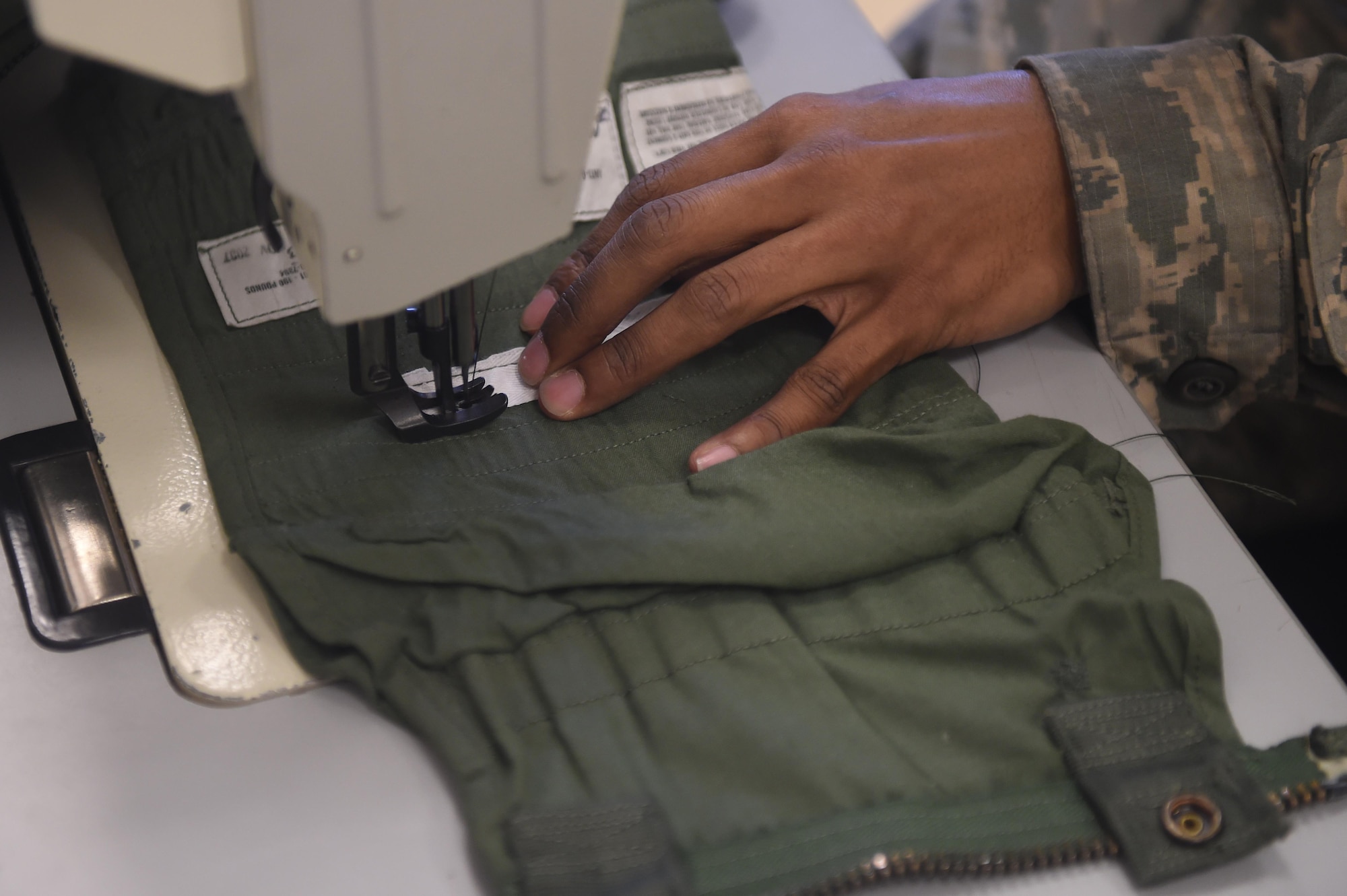 Airman 1st Class Dondrel, a 49th Operations Support Squadron aircrew flight equipment technician, sews a patch of fabric on a G-Suit at Holloman Air Force Base, N.M., July 21. AFE specialists spend two weeks in technical training learning how to operate and maintain sewing equipment. (Last names are being withheld due to operational requirements. U.S. Air Force photo by Staff Sgt. Eboni Prince)