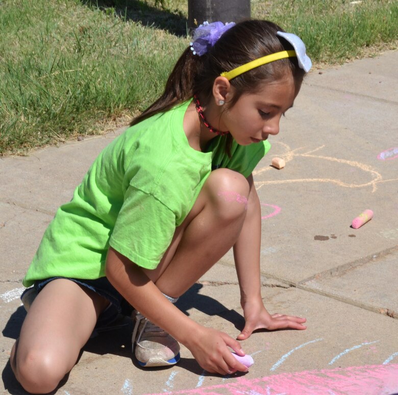 Brooke Sense draws on the sidewalk outside the Schriever Child Development Center during a field day event Monday, June 27, 2016. The Schriever School Age Care program hosted the event and invited the Ellicott summer program to the base in an effort to build the relationship between the two programs. (U.S. Air Force photo/Brian Hagberg)