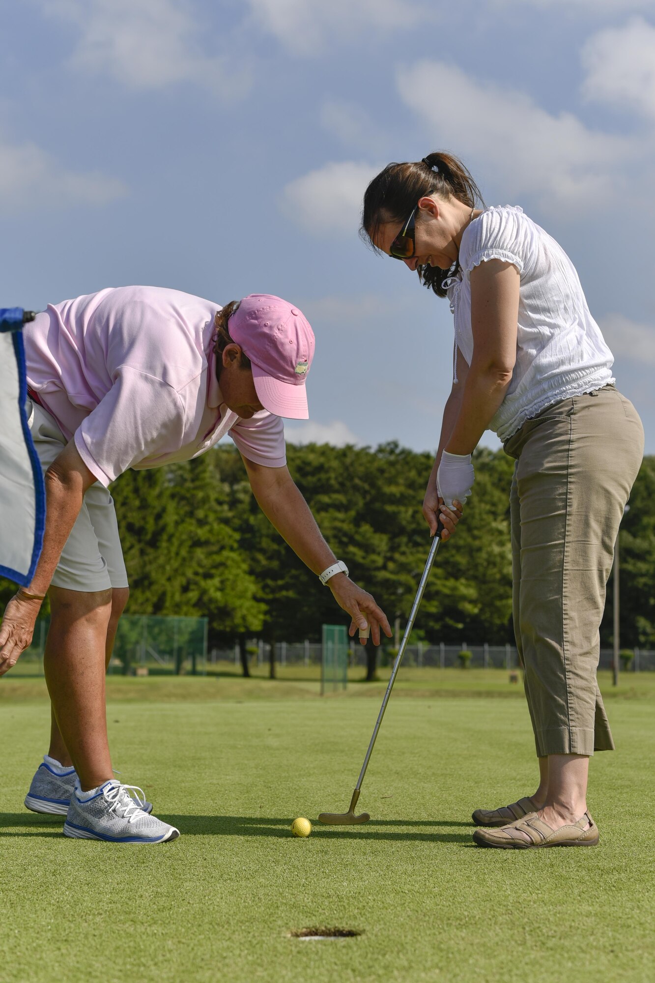 (Right) Kristi Rogers, event participant, receives instruction from Amy Reid, professional golfer, before putting at the Ladies Professional Golf Association golf clinic at Yokota Air Base, Japan, June 23, 2016. Rogers was able to receive one-on-one training during a round of golf. (U.S. Air Force photo by Staff Sgt. Michael Washburn/Released)