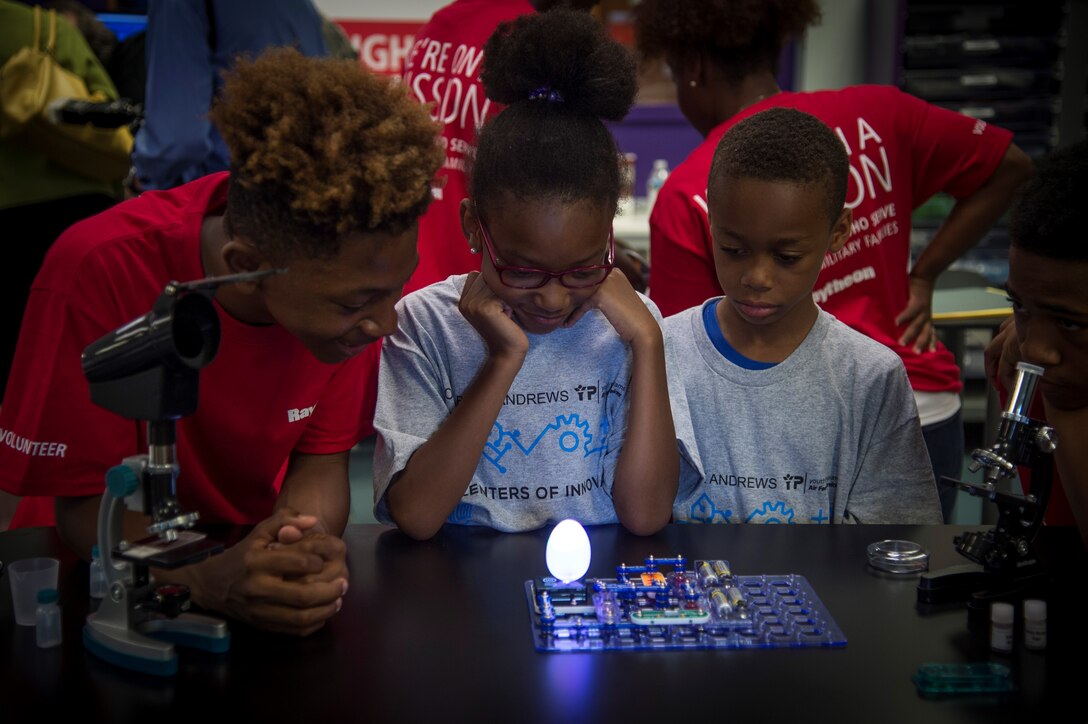 Children gather around an experiment during the opening of the Center of Innovation at the Joint Base Andrews Youth Center, here, June 24, 2016. The center will be available to approximately 140 children from the ages of 12-19 and can hold 25 students at any given time. (U.S. Air Force photo by Senior Airman Mariah Haddenham)