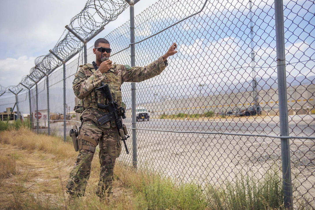 Air Force Staff Sgt. Gary Allsbrook shakes the fence to check the tactical automated security system during a security patrol on the flightline at Bagram Airfield, Afghanistan, June 27, 2016. Allsbrook and other security forces airmen conduct daily checks on the TASS systems to assure it operates properly. Allsbrook is assigned to the 455th Expeditionary Security Forces Squadron, quick reaction force. Air Force photo by Senior Airman Justyn M. Freeman