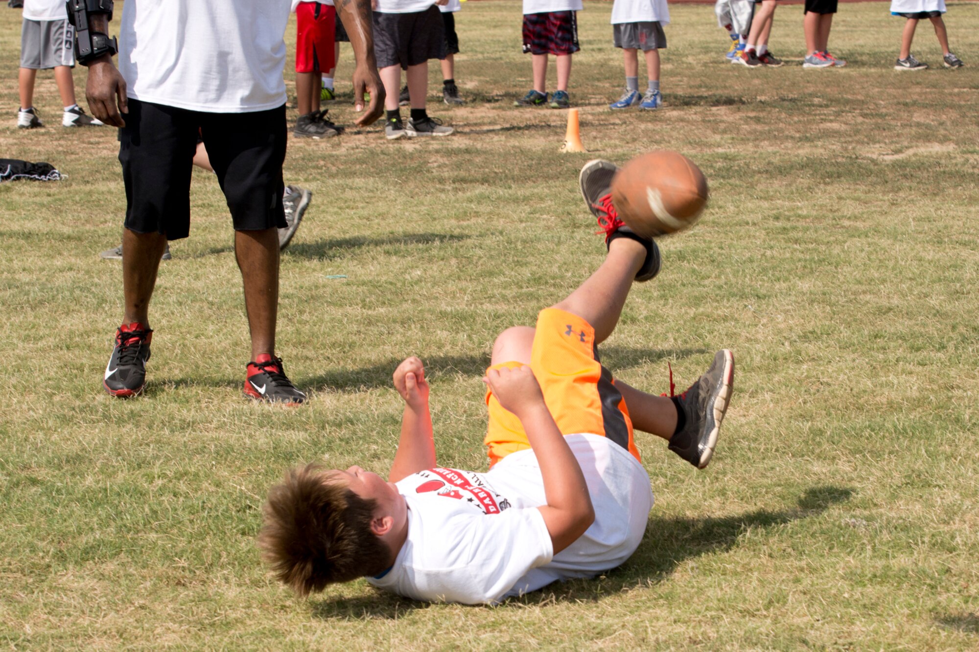 A camper trips and falls during the Darren McFadden Football ProCamp at Little Rock Air Force Base, Ark., June 23, 2016. McFadden, a running back for the Dallas Cowboys of the National Football League, hosted the two-day event, which offered instruction on fundamental skills and the finer points of football for the military children. (U.S. Air Force photo by Master Sgt. Jeff Walston/Released)