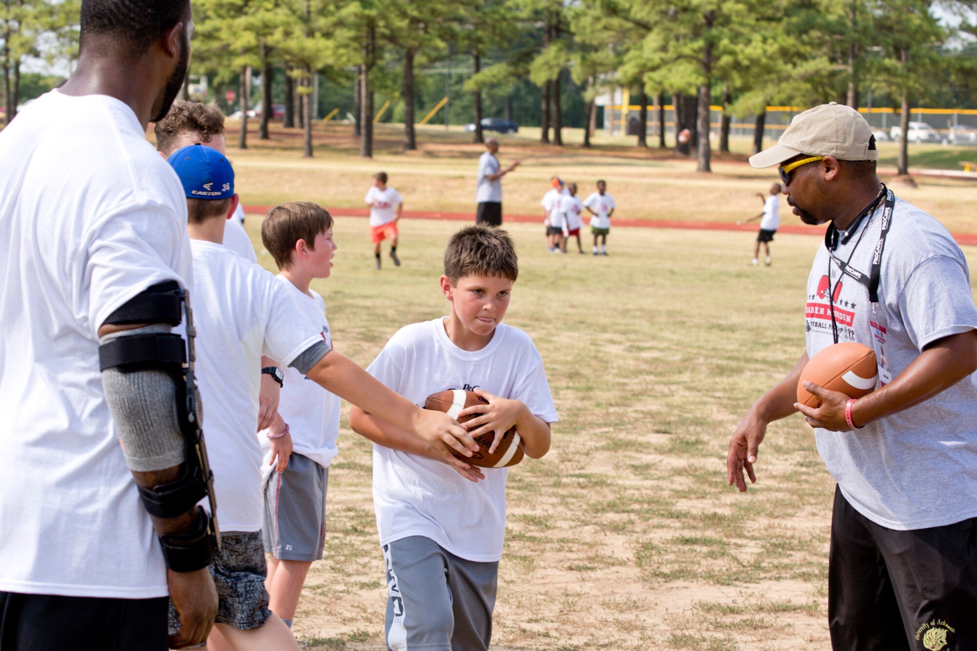 Michael Gramsch, son of Tech. Sgt. Jacqueline Langston, 96th Aerial Port Squadron, training manager, takes a handoff during the Darren McFadden Football ProCamp held at Little Rock Air Force Base, Ark., June 23, 2016. More than 100 campers attended the two-day event, which was free to military children in grades 1-8, offered instruction on fundamental skills and the finer points of football. (U.S. Air Force photo by Master Sgt. Jeff Walston/Released)